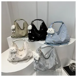 Five pleated shoulder bags in green, blue, white, black, and silver with butterfly charms