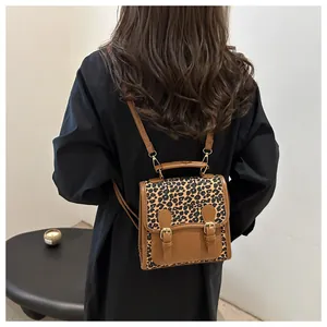 Detail of leopard print patchwork backpack with brown leather straps and metal buckle