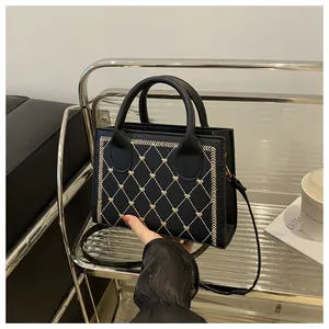 Détail d'un sac bandoulière matelassé noir avec broderie cœur dorée et poignée