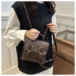 Detail of trendy leopard print backpack with brown leather straps and metal buckles