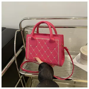 Détail du sac bandoulière rose fuchsia avec matelassage en losanges et broderie cœur