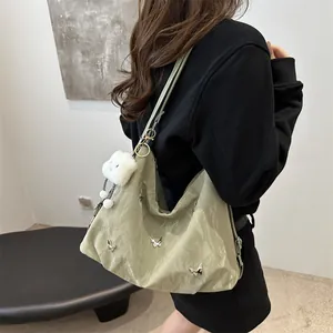 Light green pleated tote bag with silver butterfly charms and plush pendant on model