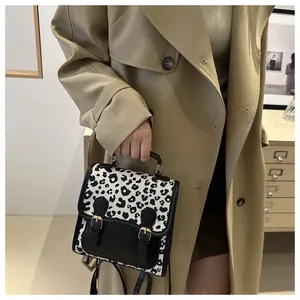 Detail of leopard print small backpack with leather straps on a khaki trench coat