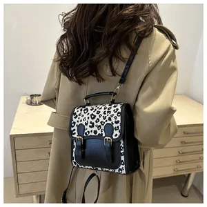 Detail of a chic leopard print flap mini backpack on a model wearing a trench coat