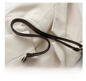 Détail de la bandoulière en cuir marron avec boucle dorée sur un sac à main en peluche