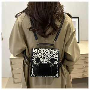Detail of small leopard print backpack with metal buckles shown on a trench coat
