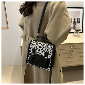 Close-up of leopard print backpack on khaki trench coat with gold buckle detail