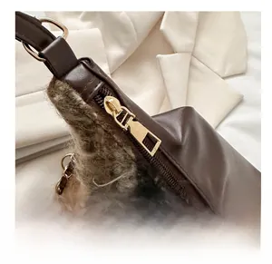 Détail de la fermeture éclair dorée et de la texture en peluche brune du sac à bandoulière