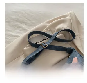 Detail of adjustable golden metal buckle on denim shoulder strap with heart patterns