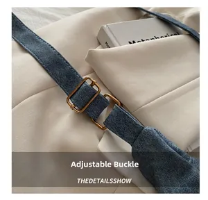 Macro shot of adjustable gold buckle on blue denim texture crescent bag strap