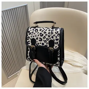 Detail of vintage faux leather mini backpack featuring leopard print flap and gold buckles