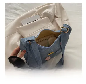 Internal storage detail of denim crescent bag with colorful heart patches and zip closure