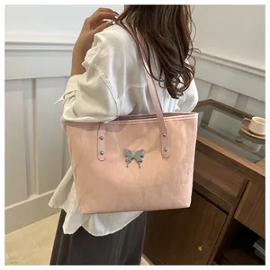 Close-up of light pink tote bag featuring a decorative silver butterfly buckle and metallic finish