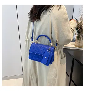 Detail of bright blue PU leather handbag featuring embossed fashion text and woven handle