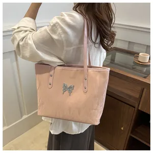Detailed texture of pink tote bag featuring a silver butterfly charm and crinkled finish