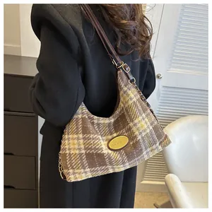 Détail d'un sac hobo à carreaux marron avec boucles dorées et bandoulière chaîne
