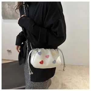 Detailed side view of white drawstring crossbody bag with colorful heart embroidery