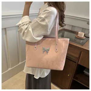 Pink commute tote bag with silver butterfly buckle shown on a shoulder in a room