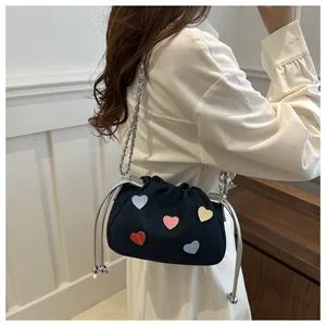 Macro detail of denim bucket bag with colorful heart patches and silver chain strap