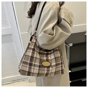 Gros plan du sac bandoulière en tweed à carreaux marron avec logo doré et chaîne