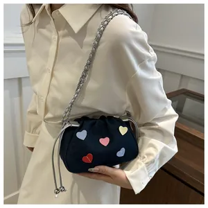 Detail view of denim drawstring bucket bag featuring colorful embroidered heart patches
