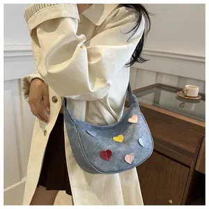Detail view of a grey felt crescent bag with colorful heart patches worn with a beige coat