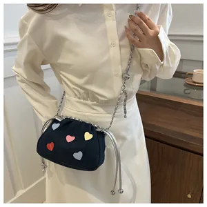 Detail of blue denim bucket bag featuring colorful heart patches and silver chain strap