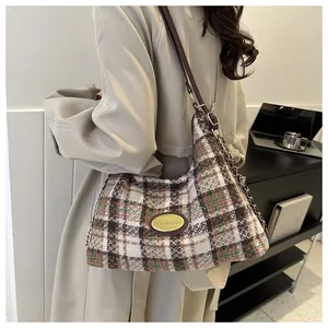 Sac hobo en tweed à carreaux marron porté épaule avec emblème doré du logo