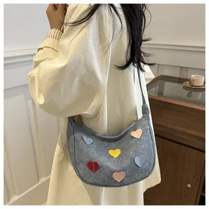 Detail view of crescent crossbody bag featuring colorful heart patches and fine stitching