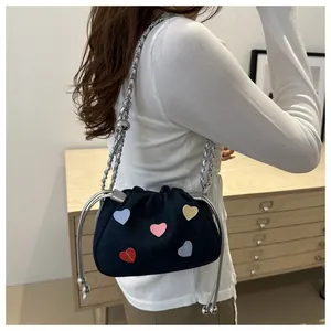 Detail of denim bucket bag with colorful heart patches and silver chain strap for women