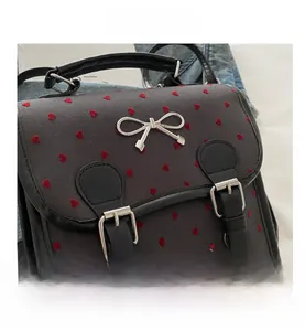 Detail of grey fabric bag with red heart embroidery and silver bow metal clasp