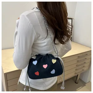 Back view of a mini denim drawstring bag with colorful 3D hearts and silver chain strap