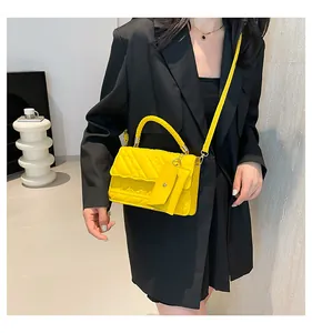 Detail of yellow quilted fashion handbag with top handle and small coin purse attachment