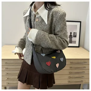 Lifestyle shot of grey hobo bag with colorful heart patches and black shoulder strap