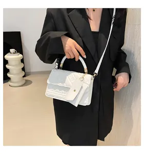 Detail of white PU leather crossbody bag with geometric embossed textures and woven handle