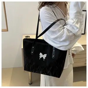 Detail showing a black crinkled fabric tote bag with a silver butterfly ornament