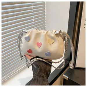 Detail of drawstring bucket bag with colorful heart patches and silver chain strap
