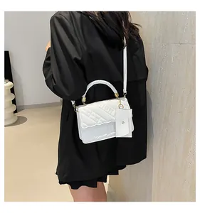 Close-up of white quilted handbag with FASHION relief and matching mini charm bag
