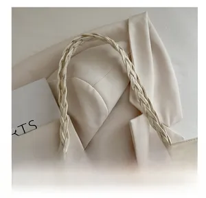 Close-up of a woven handle on a minimalist tote bag with wave-patterned embroidery