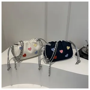 Detail of cream and navy mini bucket bags with colorful heart patches and silver chain straps