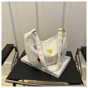 Detail of white PU leather crescent bag with colorful heart patches and wide strap