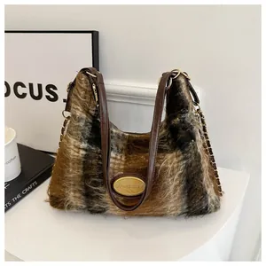Détail d'un sac à bandoulière en peluche à carreaux marron avec fourrure douce et plaque dorée