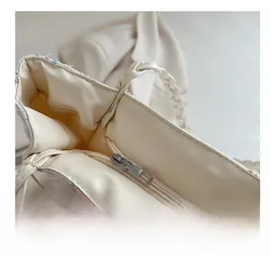 Detail view of smooth metal zipper and woven handle on beige minimalist tote bag