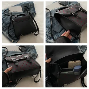 Detail view of black faux leather backpack with red heart embroidery and silver bow buckle