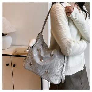 Détail du sac cabas gris argenté avec papillons métalliques et breloque pompon blanc