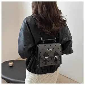 Mini gray backpack with polka dots and bow detailing worn over a black leather jacket