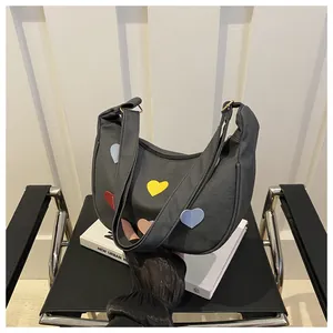 Detail of black crescent hobo bag with colorful heart patches on a modern chair