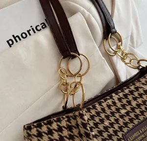 Detailed close-up of golden metal rings and chain connecting the houndstooth tote strap