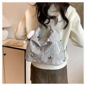 Sac à bandoulière plissé gris argenté avec breloques papillon dorées et pompon doux