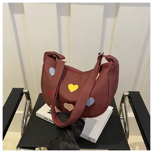 Close-up of crescent hobo bag in burgundy suede with colorful heart patchwork detail